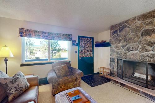 a living room with a stone fireplace and a chair at Hi Country Haus 6-15 in Winter Park
