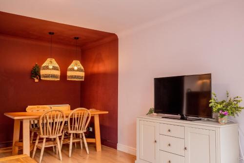 a dining room with a table and a flat screen tv at 1 Hales Orchard in Worcester