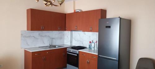 Una cocina con gabinetes de madera y un refrigerador de acero inoxidable. en Keti APT, en Kashari