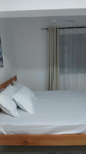 ディアニ・ビーチにあるImani stay cations Dianiの部屋にある白いシーツと枕が置かれたベッド