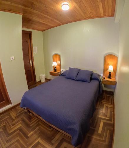 a bedroom with a bed with blue sheets and two lamps at Rajutuna Inn in Huaraz