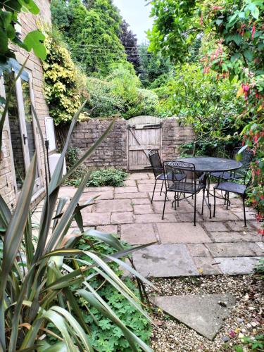 a patio with a table and chairs in a garden at Fig Tree Cottage 