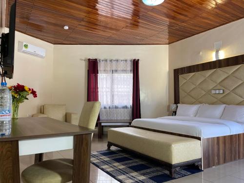 a bedroom with a bed and a desk and a table at C3 Resort Hotel Foumbot 