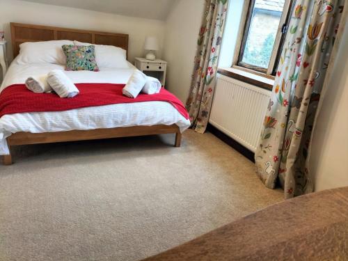 a bedroom with a bed with a red blanket and a window at Fig Tree Cottage 