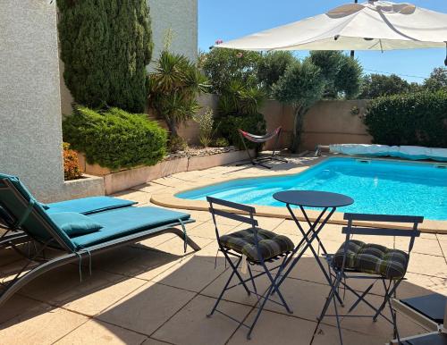 a pool with two chairs and a table and an umbrella at RIBA D'AUDE SPA privatif proximité aéroport et de la Cité médiévale in Carcassonne