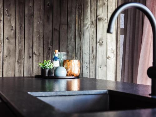 a sink in a kitchen with a wooden wall at La Rurée in Heure
