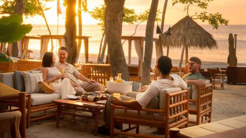 a group of people sitting around a table on the beach at Villa Tortuga in Nacascolo