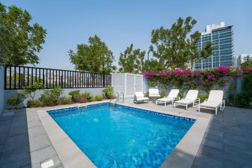 a swimming pool with lounge chairs next to a building at Private Pool Paradise Villa! Dubai Mall in a Flash! Complimentary Full Mid-Stay Refresh for 1 week stay in Dubai