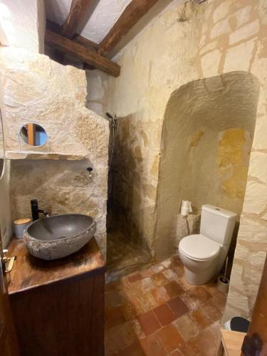 a stone bathroom with a sink and a toilet at Le chant du troglodyte in Saumur