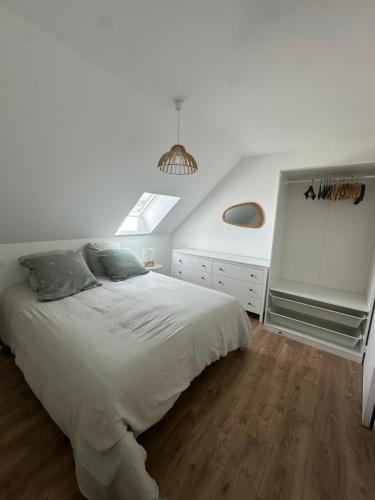 a white bedroom with a large bed and a window at Maison à Dol de Bretagne in Dol-de-Bretagne