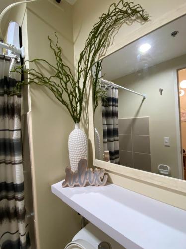 a bathroom with a mirror and a vase on a sink at AVIDA TOWERS - Aspira Tower1 in Cagayan de Oro