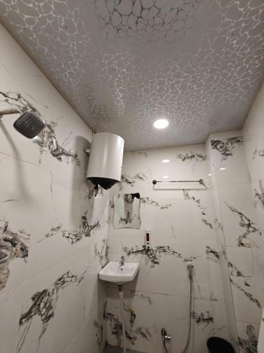 a white bathroom with a sink and a ceiling at Stay Kailash -Vishwanath Temple View in Varanasi