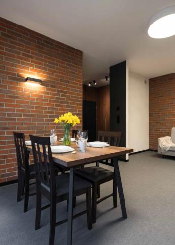 a dining room table with chairs and a brick wall at Apartamenty Parkowe in Żywiec