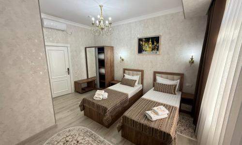 Un dormitorio con dos camas y una lámpara de araña. en Mubina East Hotel, en Bukhara