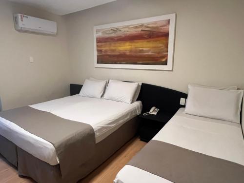 a room with two beds and a painting on the wall at Hotel Galícia in Rio de Janeiro