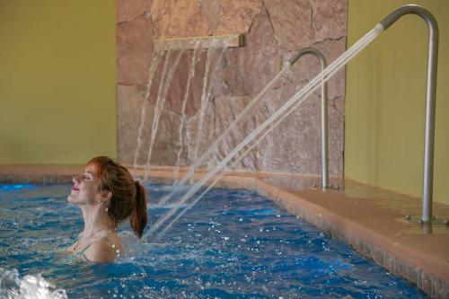 a woman in a swimming pool with a water hose at Don Numas Posada & Spa in San Lorenzo