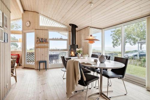 a dining room with a table and chairs and windows at 40353-Juelsminde-Niels-Rasmussens-Vej-127 in Sønderby