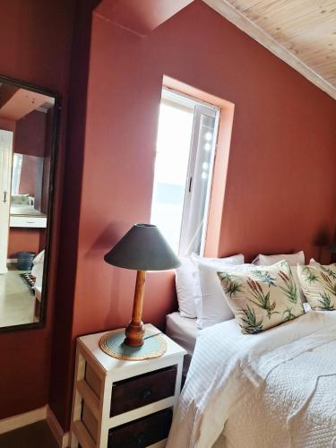 a bedroom with a bed and a mirror and a lamp at Tweede Lente in St Helena Bay