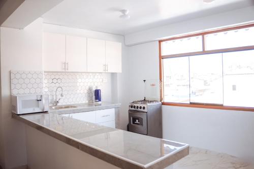 a white kitchen with a sink and a stove at duplex acogedor in Cusco
