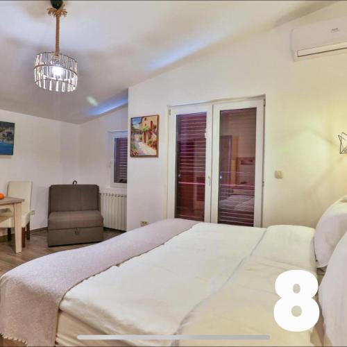 a bedroom with a large white bed and a chair at Villa Kosta in Budva