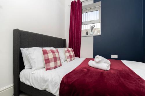a bed with a red and white blanket and a window at The Maple Haven – Spacious 3BR with FREE Parking in Jarrow