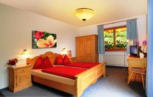 Un dormitorio con una gran cama de madera con almohadas rojas en Hotel Mair Am Bach, en Bresanona