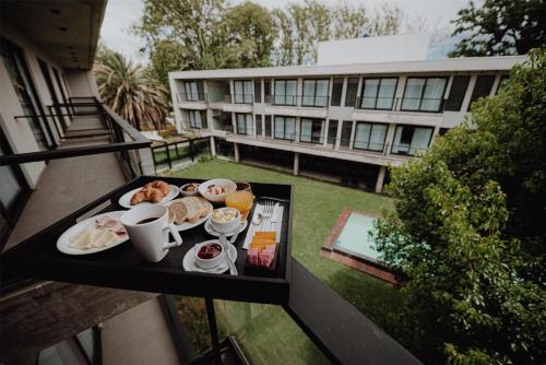 a tray of breakfast food on a balcony of a building at La Urumpta Hotel, AKEN MIND in Río Cuarto