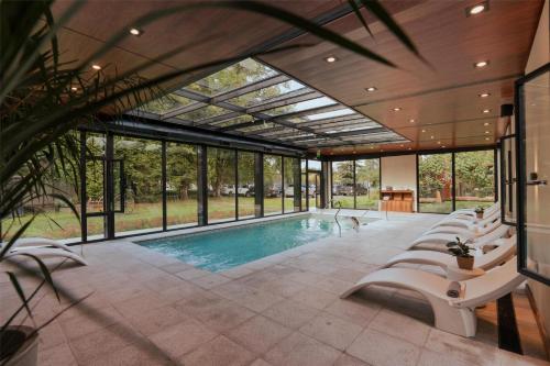 an indoor pool with white chairs and a large room with windows at La Urumpta Hotel, AKEN MIND in Río Cuarto