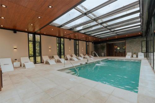 an indoor pool with a glass ceiling and white chairs at La Urumpta Hotel, AKEN MIND in Río Cuarto