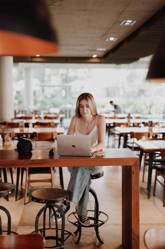 a woman sitting at a table with a laptop at La Urumpta Hotel, AKEN MIND in Río Cuarto