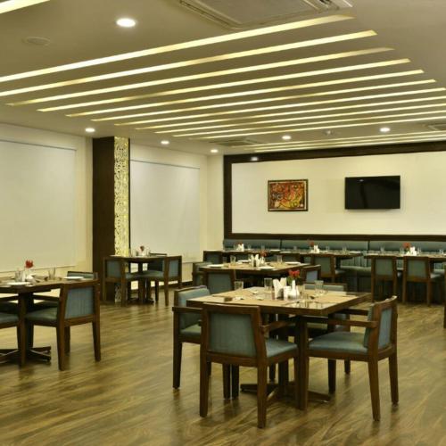 a dining room with tables and chairs and a screen at Hotel Nysha Delhi in New Delhi