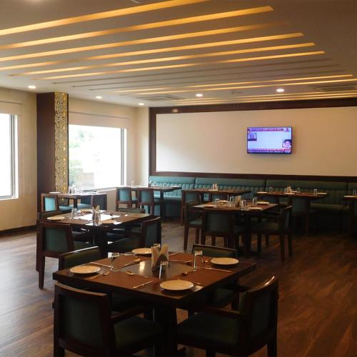 a restaurant with tables and chairs and a flat screen tv at Hotel Nysha Delhi in New Delhi