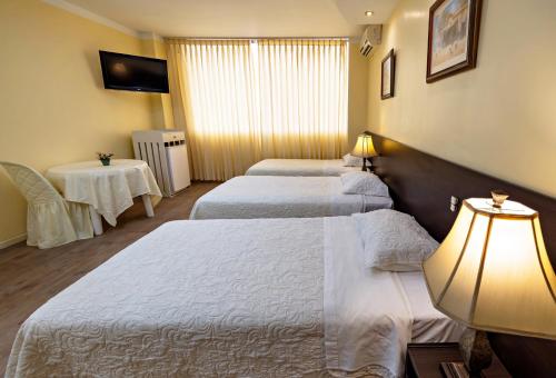 a hotel room with two beds and a lamp at Gran Bolivar Hotel - Trujillo, Perú in Trujillo