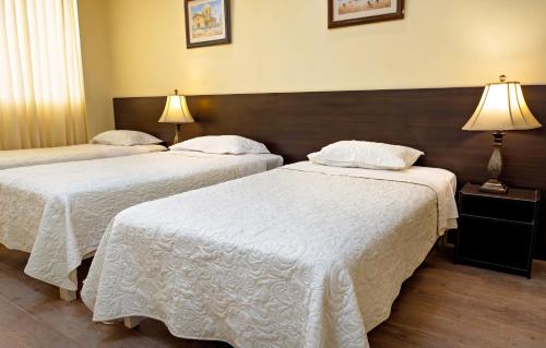 a hotel room with two beds with white sheets at Gran Bolivar Hotel - Trujillo, Perú in Trujillo