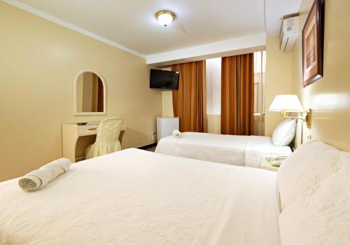 a hotel room with two beds and a desk at Gran Bolivar Hotel - Trujillo, Perú in Trujillo