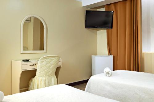 a room with two beds and a desk and a mirror at Gran Bolivar Hotel - Trujillo, Perú in Trujillo