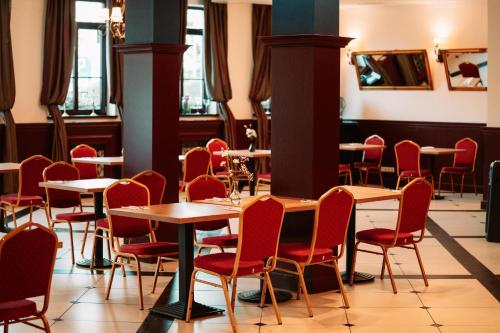 a dining room with tables and red chairs at Villa Tradycja in Białystok