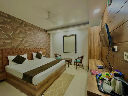 a bedroom with a bed and a table and a television at Hotel Nysha Delhi in New Delhi