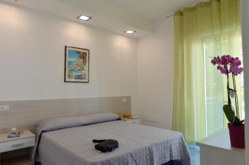 a bedroom with a bed and a vase with purple flowers at Acquamarine Maiori Amalfi Coast in Maiori