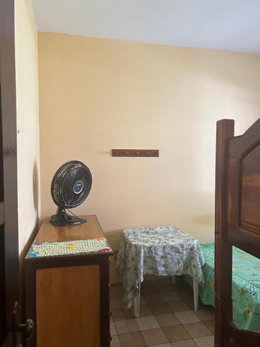 a bedroom with a table and a fan on a dresser at Casa de veraneio in Salinópolis