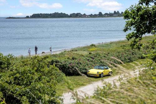 a yellow car parked on a beach next to the water at 30020-Malling-Hyldevaenget-17 in Malling