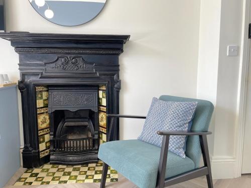 a chair in front of a fireplace with a clock at Melbury Rooms & Studios in Exeter