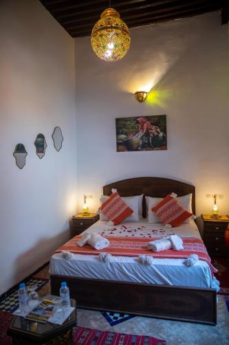 a bedroom with a bed with two tables and a chandelier at Dar Lalamoune in Fès