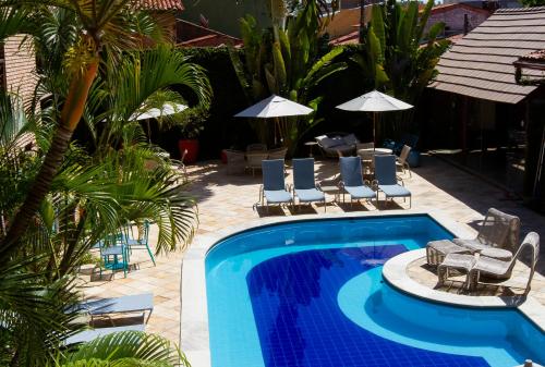 a pool with chairs and umbrellas in a resort at Hotel Areias Belas in Maragogi