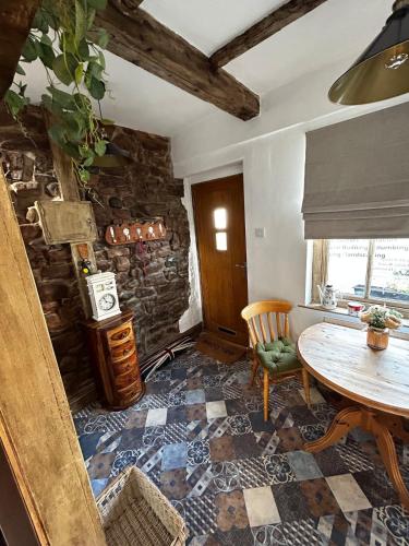 a dining room with a table and a stone wall at Nettle Cottage in Heysham