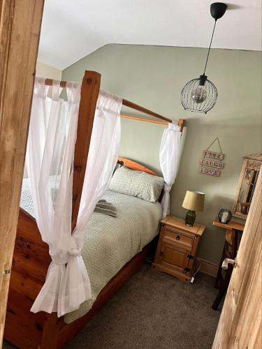 a bedroom with a bed with white curtains at Nettle Cottage in Heysham