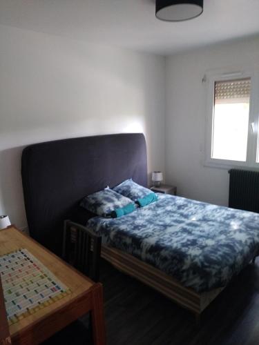 a bedroom with a bed and a table and a window at Appartement dans copropriété arborée in Saint-Jacques-de-la-Lande