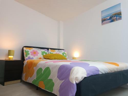 コスタ・ダ・カパリカにあるHappy Day Suite Hostelのベッドルーム1室(カラフルなシーツと枕のベッド1台付)