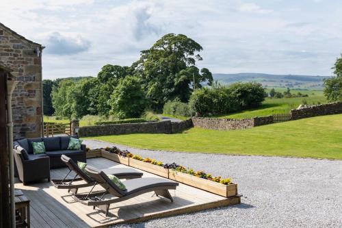 a patio with a couch and chairs and a garden at Tithe Barn, Skipton in Skipton