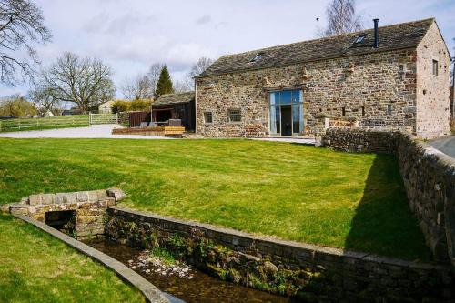 a stone house with a grass yard in front of it at Tithe Barn, Skipton in Skipton